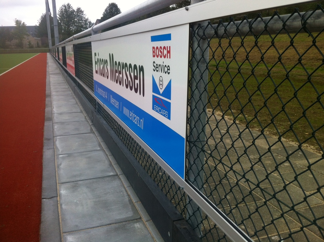 Reclame-ophangsysteem Pro 12 Reclamerails PRO. Hier gemonteerd op gaashekwerk.