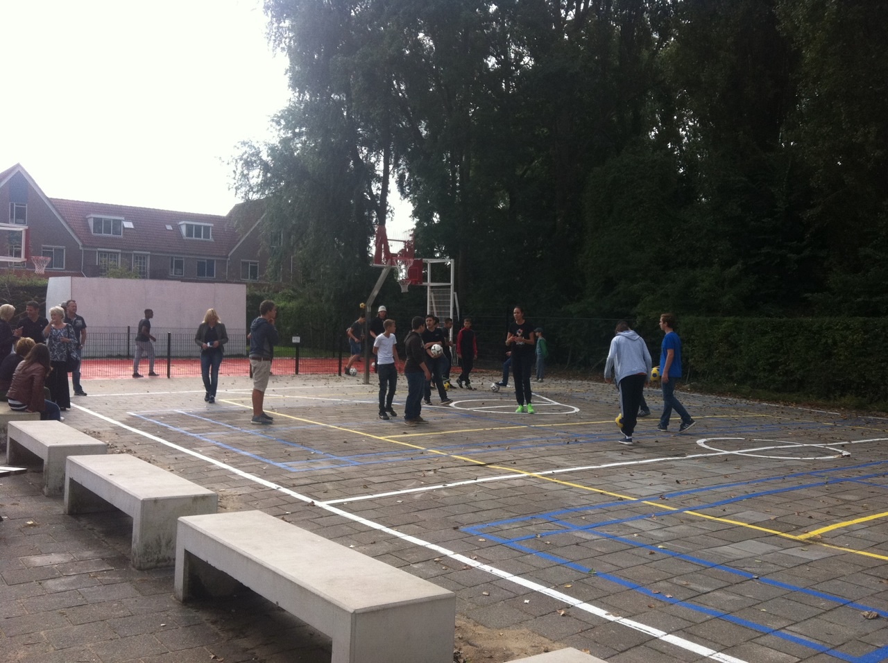Beton banken 6 U-banken geplaatst in Amsterdam bij een door ons sportief ingericht schoolplein. Pannakooi met basketbal op de achtergrond en 2 losse basketbalpalen en sportbelijningen voor diverse sporten.