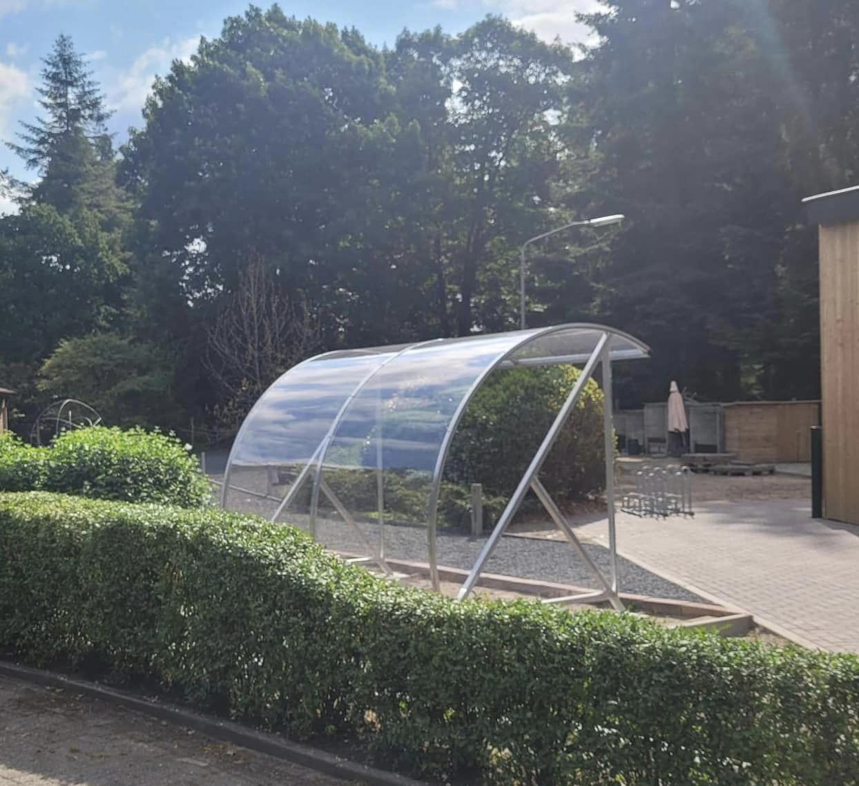 Fietsoverkapping BF1000 - AANBIEDING 43 De BF1000 fietsoverkapping, die is uitgerust met thermisch verzinkt staal en slagvast transparant polycarbonaat, is niet alleen perfect voor fietsenstalling, maar kan ook ingezet worden als rookabri voor groepen van 6 tot 8 personen.