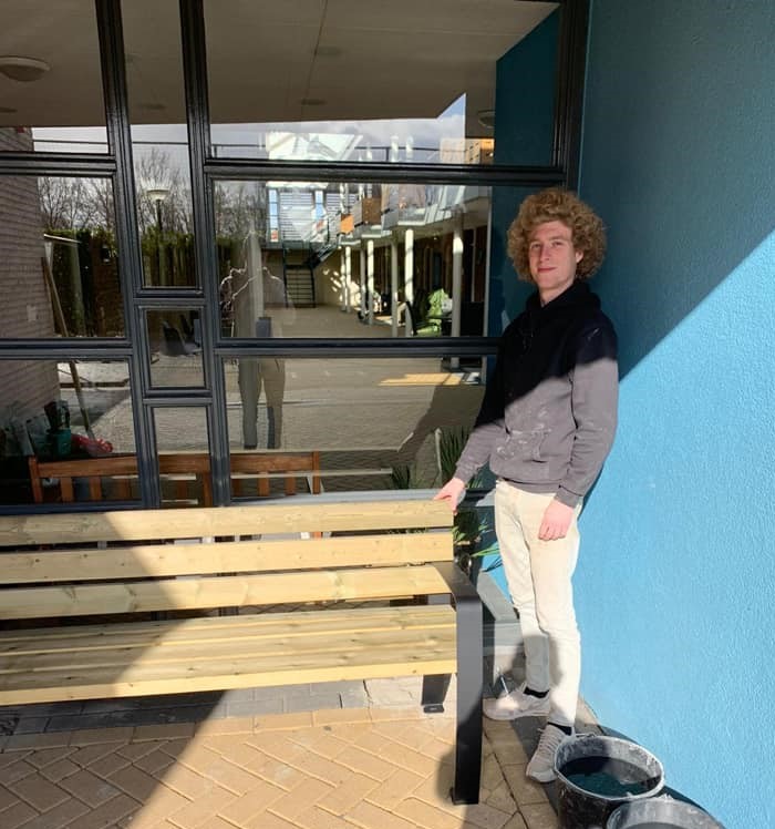 Parkbank Sofia 10 1 van onze monteurs naast de geplaatste parkbank. Naast de levering van uw straatmeubilair, kunnen wij ook de montage voor u verzorgen.