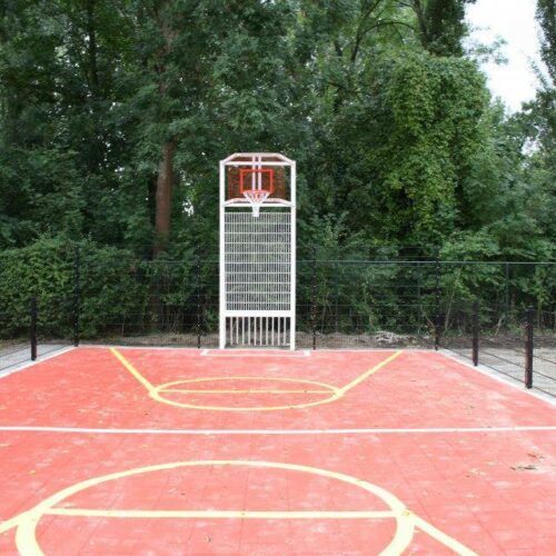 Sportvloercoating 63 Pannakooi met basketbal en een rood gecoate speelvloer en witte voetbal-belijningen en gele basketbal-belijningen bij school in Amsterdam.