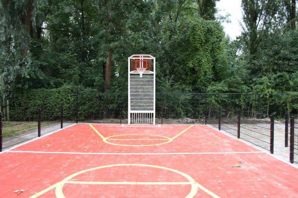 Sportvloercoating 26 Pannakooi met basketbal en een rood gecoate speelvloer en witte voetbal-belijningen en gele basketbal-belijningen bij school in Amsterdam.