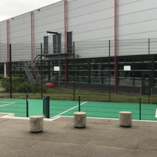 Sportvloercoating 40 Onze Premium voetbalkooi met basketbal, voorzien van een groene Granuplast rolcoating en witte belijningen.