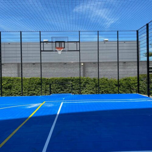 Sportvloercoating 62 Voetbalkooi met een blauwe Granuplast-coating met voetbal en basketbalbelijningen.